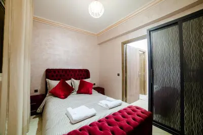 a large bed with red pillows and a red couch at Charming and quiet apartment 1 in Marrakech