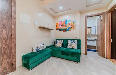 a living room with a green couch in a room at Appartement cosy moderne piscine in Marrakech
