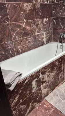 a white bath tub in a bathroom with marble tiles at Chez Houda in Marrakech