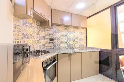 a kitchen with white cabinets and tiles on the wall at Residence Jnan Atlas gueliz in Marrakech