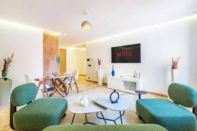 a living room with chairs and a tv on a wall at Stylish modern 1BR in gueliz in Marrakech