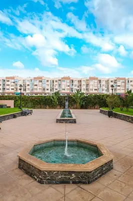 a fountain in a courtyard in front of a large building at Luxe 2-Bedroom with Pool in Marrakech in Marrakech
