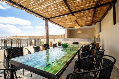 a dining table and chairs on a patio with a roof at Riad Malaika in Marrakech