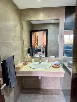 a bathroom with a sink and a large mirror at Appartement moderne dans Marrakech in Marrakech