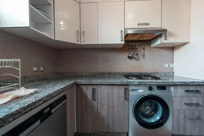 a kitchen with a washing machine and white cabinets at La maison du soleil in Oulad Akkou