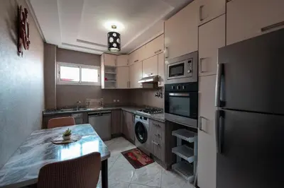 a small kitchen with a table and a refrigerator at La maison du soleil in Oulad Akkou