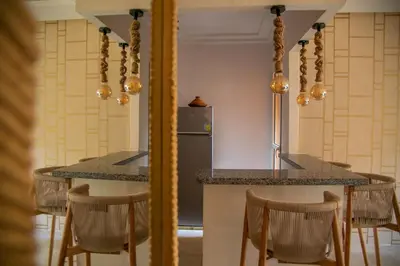 a kitchen with a counter with chairs and a refrigerator at Cozy, Nice appartement,swimming pool,Wifi in Marrakech
