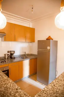 a kitchen with wooden cabinets and a stainless steel refrigerator at Cozy, Nice appartement,swimming pool,Wifi in Marrakech