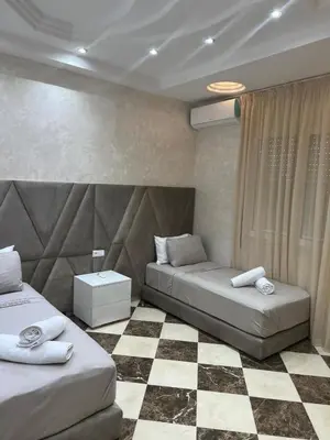 a bedroom with two beds and a checkered floor at Dar Hanane in El Gouassem