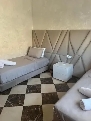 a bedroom with two beds and a checkered floor at Dar Hanane in El Gouassem
