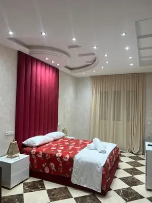 a bedroom with a large bed with a red curtain at Dar Hanane in El Gouassem
