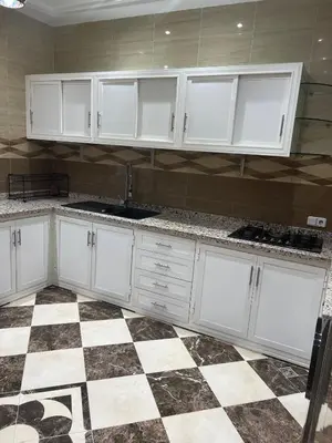 a kitchen with white cabinets and a checkered floor at Dar Hanane in El Gouassem