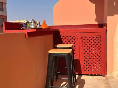 a kitchen with a red counter with stools under it at Elegant & Cosy Cocoon in Central Gueliz in Marrakech