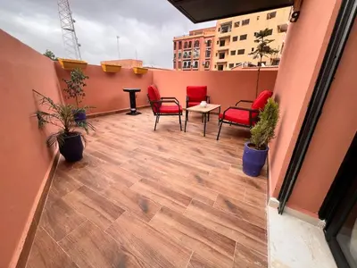a balcony with red chairs and a table on a building at Appartement Chic avec Terrasse à Gueliz in Marrakech