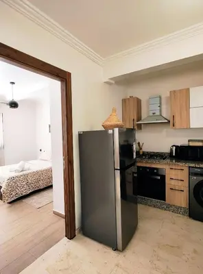 a kitchen with a stainless steel refrigerator and a bed at Studio cosy avec piscine à Gueliz in Marrakech