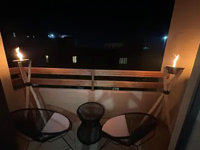 a balcony with two chairs and two tables and two candles at Appartement moderne Piscine, Wifi fibre, parking in Marrakech