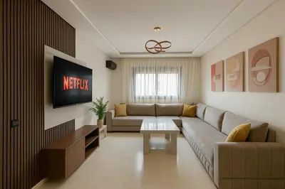 a living room with a couch and a tv at Appartement moderne Piscine, Wifi fibre, parking in Marrakech
