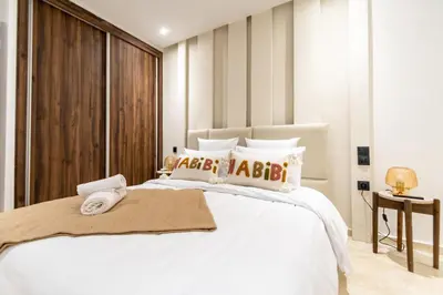 a bedroom with a white bed with a wooden headboard at Modern Apartment in Victor Hugo Walk to Gueliz City Center in Marrakech