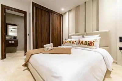 a bedroom with a large white bed and a bathroom at Modern Apartment in Victor Hugo Walk to Gueliz City Center in Marrakech
