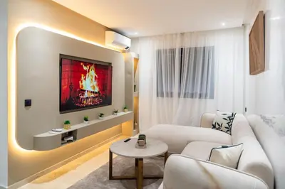 a living room with a couch and a tv on a wall at Modern Apartment in Victor Hugo Walk to Gueliz City Center in Marrakech