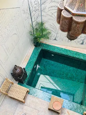 a small swimming pool with two chairs and a table at Riad Émeraude Privé 3 chambres avec piscine Médina Marrakech in Marrakech