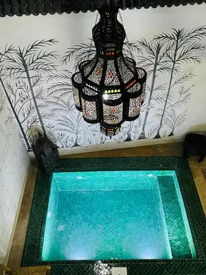 a chandelier hanging from a wall with a pool of water at Riad Émeraude Privé 3 chambres avec piscine Médina Marrakech in Marrakech