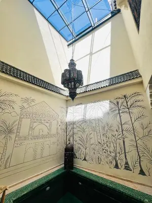 a wall with a mural of trees and a chandelier at Riad Émeraude Privé 3 chambres avec piscine Médina Marrakech in Marrakech