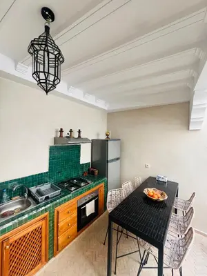 a kitchen with a table and a stove and a refrigerator at Riad Émeraude Privé 3 chambres avec piscine Médina Marrakech in Marrakech
