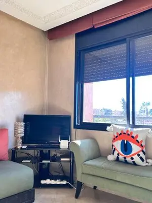 a living room with a chair and a television at Central Gueliz Apartment Bright & Peaceful in Marrakech