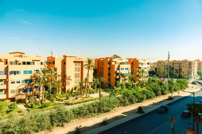 a city with buildings and palm trees and a street at Chic Marrakech Getaway with Pool, Gym & Security in Marrakech