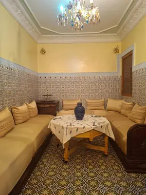 a living room with two beds and a chandelier at Lalla Fatima - a deux pas de la Bahia in Marrakech