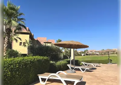 a group of lounge chairs and an umbrella at Ehden Properties - Appt d'exception dans l'incontournable Prestigia in Marrakech