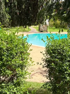 a blue swimming pool in the middle of a park at A Cosy Maison avec un accès direct à la piscine in Marrakech