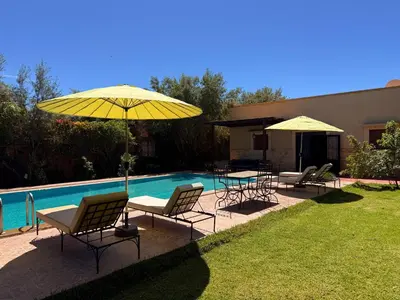 a group of chairs and umbrellas next to a pool at DAR ENNAGA - Havre de paix, avec piscine chauffée , à 10 minutes de Marrakech in Marrakech