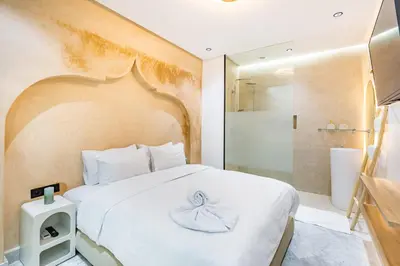 a bedroom with a large white bed and a shower at Duplex Confort, Jacuzzi à 5min de Majorelle&Médina in Marrakech