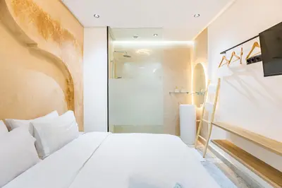 a bedroom with a white bed and a shower at Duplex Confort, Jacuzzi à 5min de Majorelle&Médina in Marrakech