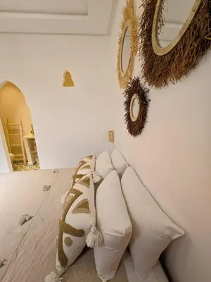 a room with white pillows and a wall with a mirror at Dar laarbi Kasbah in Marrakech