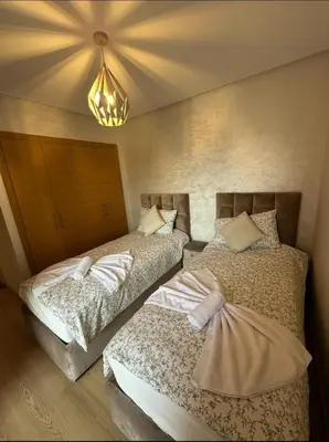 a bedroom with two beds and a chandelier at Appartement Marrakech in Marrakech