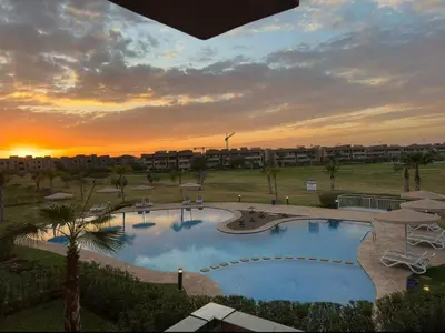 a large swimming pool with a sunset in the background at Appartement Marrakech in Marrakech