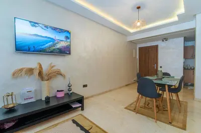a living room with a table and a tv on the wall at Gueliz Train Station - Swimming Pool - Cosy in Marrakech