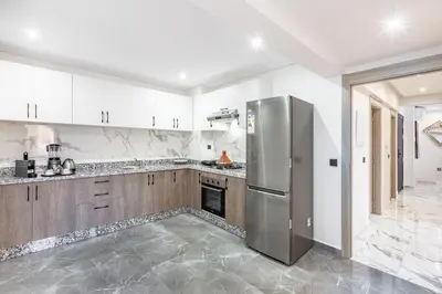 a kitchen with white cabinets and a stainless steel refrigerator at Luxury House avec Piscine et Terrasse in Marrakech