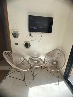 two chairs and a table with a tv on a wall at Lovely apartment N15 in Marrakech