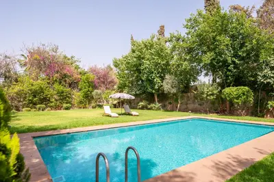 a swimming pool with two chairs and an umbrella at Villa Jnan Targa Pool & Garden in Marrakech