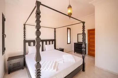 a bedroom with a canopy bed with white sheets at Villa Jnan Targa Pool & Garden in Marrakech