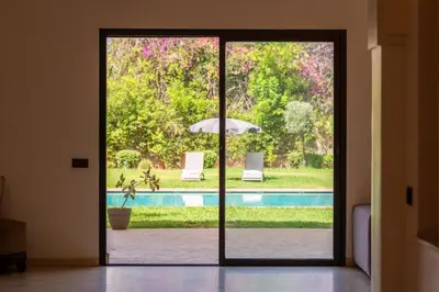 an open door leading to a pool with an umbrella at Villa Jnan Targa Pool & Garden in Marrakech