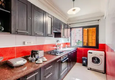 a kitchen with black cabinets and a red wall at Appartement Moderne & Spacieux au Cœur de Guéliz et Proche Majorelle in Marrakech