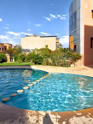 a swimming pool with rocks in front of a building at Marrakech in Marrakech
