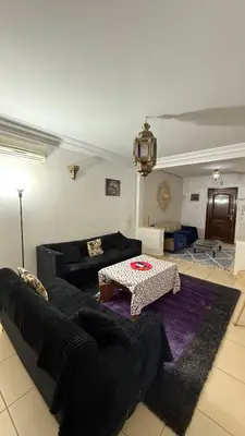 a living room with a black couch and a table at Appartement 6 personnes piscine hivernage Marrakech in Marrakech