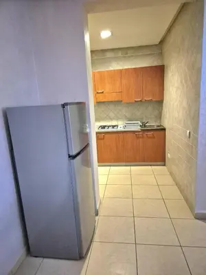 a stainless steel refrigerator in a kitchen with wooden cabinets at Appartement 6 personnes piscine hivernage Marrakech in Marrakech