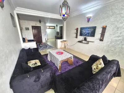 a living room with a black couch and a table at Appartement 6 personnes piscine hivernage Marrakech in Marrakech
